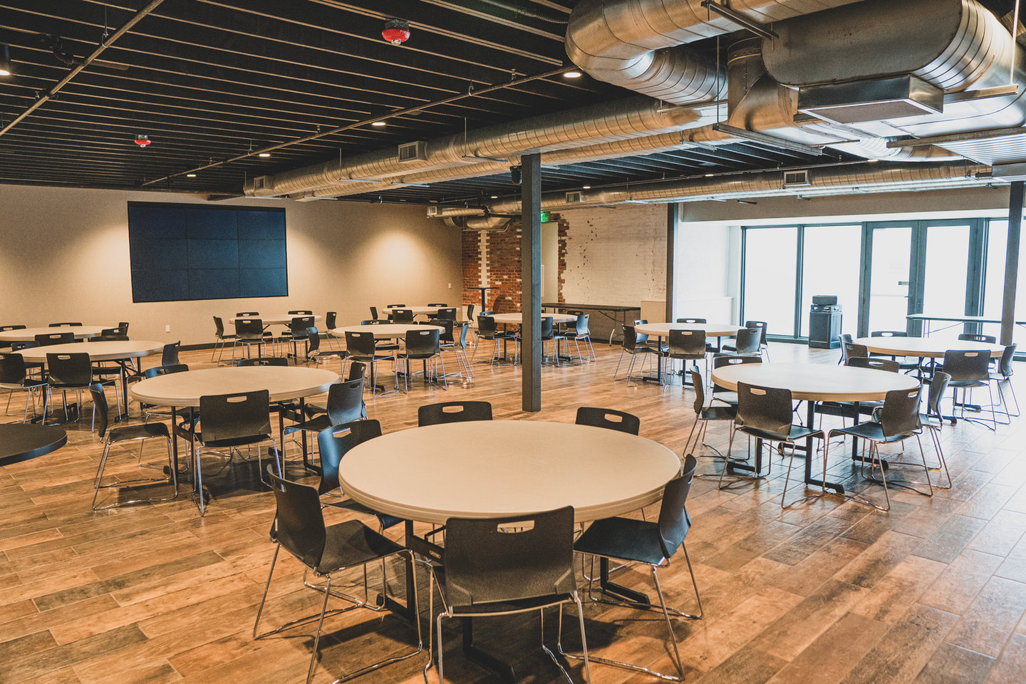 Upper Reception Hall at Glacial Till Cider House in Ashland with round tables and large windows
